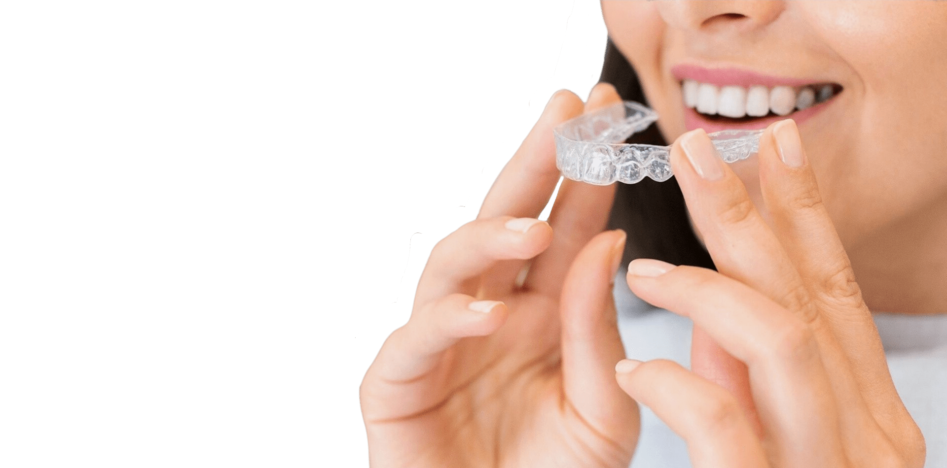 A woman holding her clear aligner in front of her teeth
