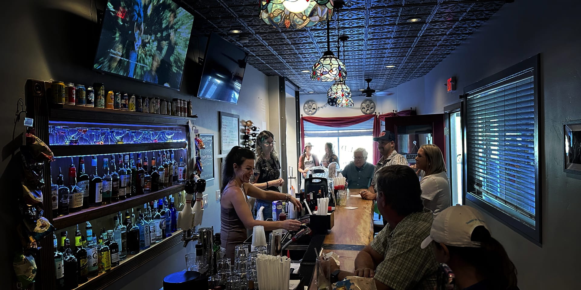 The interior of Caldwells Liberty Bar with a bartender serving a variety of clients.