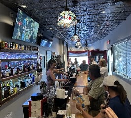 A view of the bar showing a bartender serving a variety of clients.