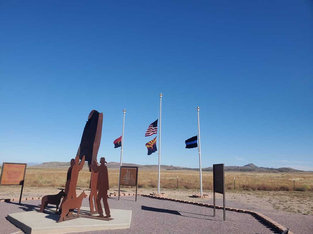 Chino Valley Monument with clear skies as the flags wave before a backdrop of mountains