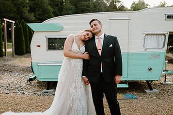 happy couple post in front of camper