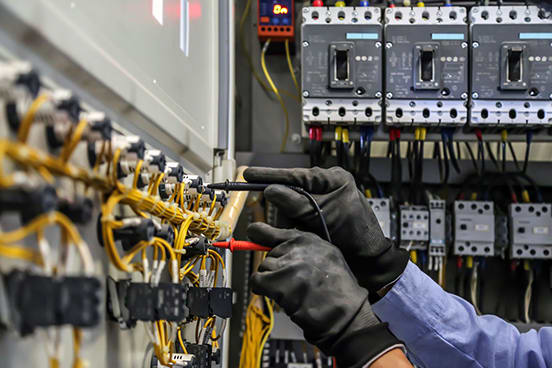 Hands holding electrical probes against a circuit