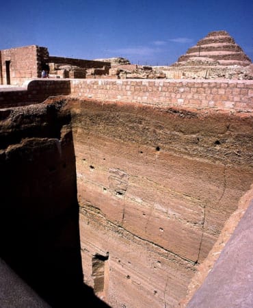 An excavation in Giza with a stepped pyramid in the background.