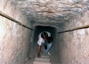 The author climbing up a ladder inside a deep pit in a pyramid