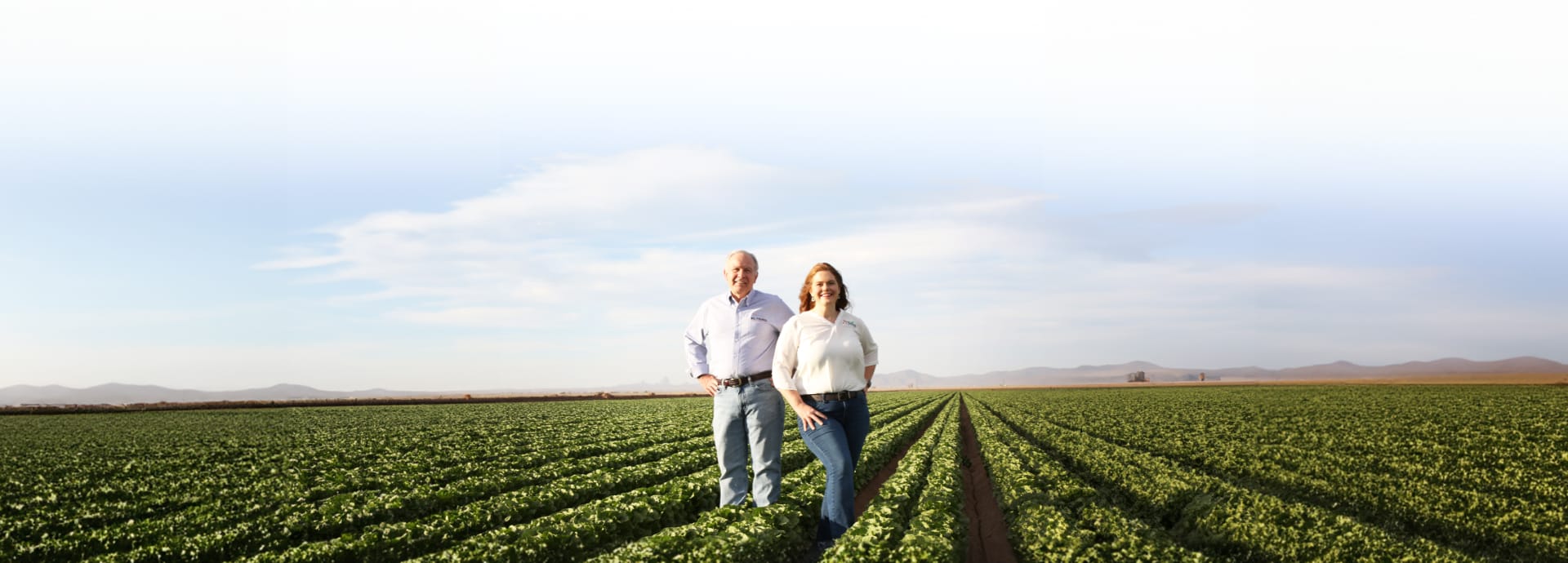 Vic Smith and Kristen Eshaya standing in a field of leafy greens.