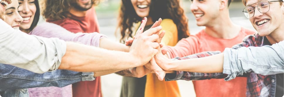 A group of people in a circle with their hands held together in the middle