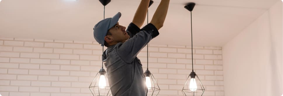 A professional electrician in a home working on overhead lights