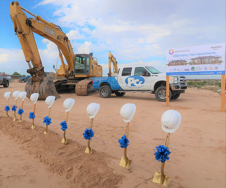 Hats on golden shovels in dirt at a ground breaking ceremony with a PCC Truck and equipment in the background