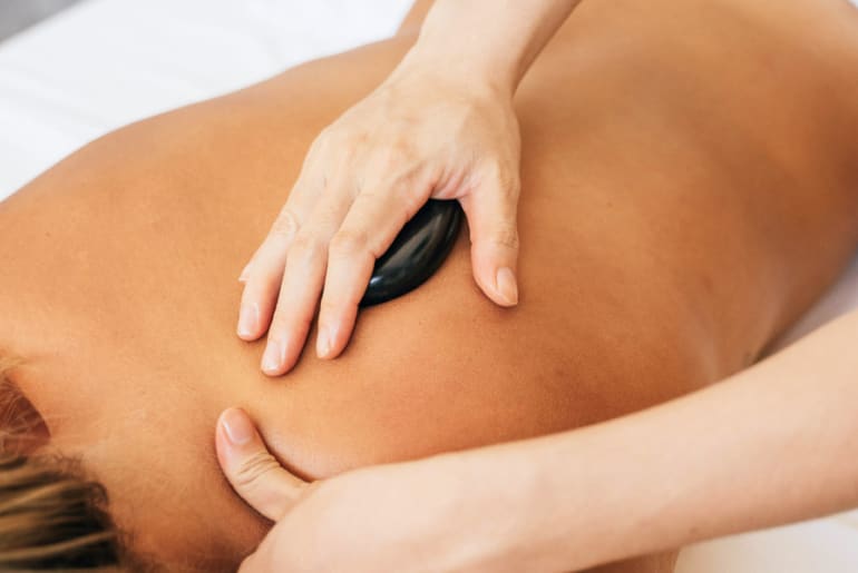 A woman receiving a hot stone massage on her back from a therapist at Healing Waters in Pagosa Springs, Colorado.