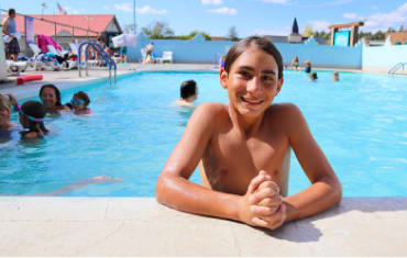 A smiling shirtless child enjoying a hot spring water pool at Healing Waters in Pagosa Springs Colorado.