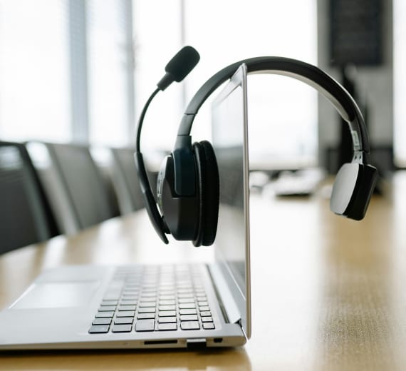 A headset hanging from a laptop, representing virtual receptionist and answering services.