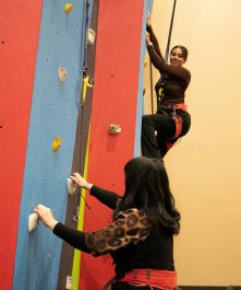 Two young women smile at each other while enjoying the challeng of climbing the climbing wall at cocopah wild river