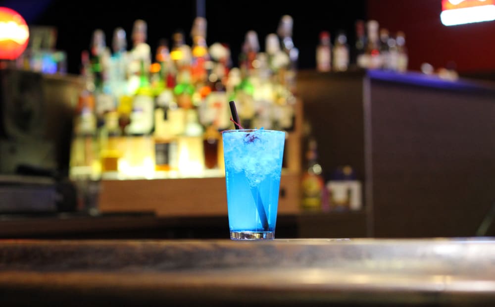 A light blue cocktail in a glass on the bar at Wild River Sports Bar.