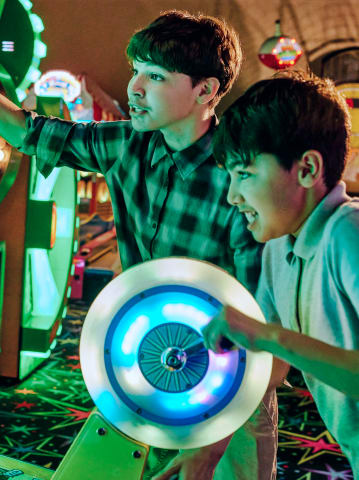 Two young boys playing a competitive game in the Cocopah Wild River Arcade